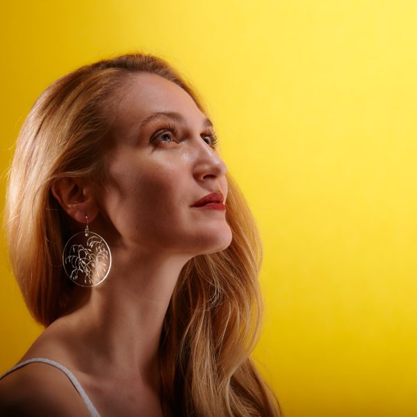 Fille avec des boucle d'oreille en plexiglas transparent gravé à la main de graminées